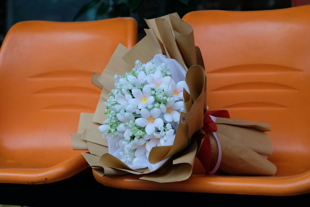 A beautiful bouquet of white flowers wrapped in paper on vibrant orange seats.